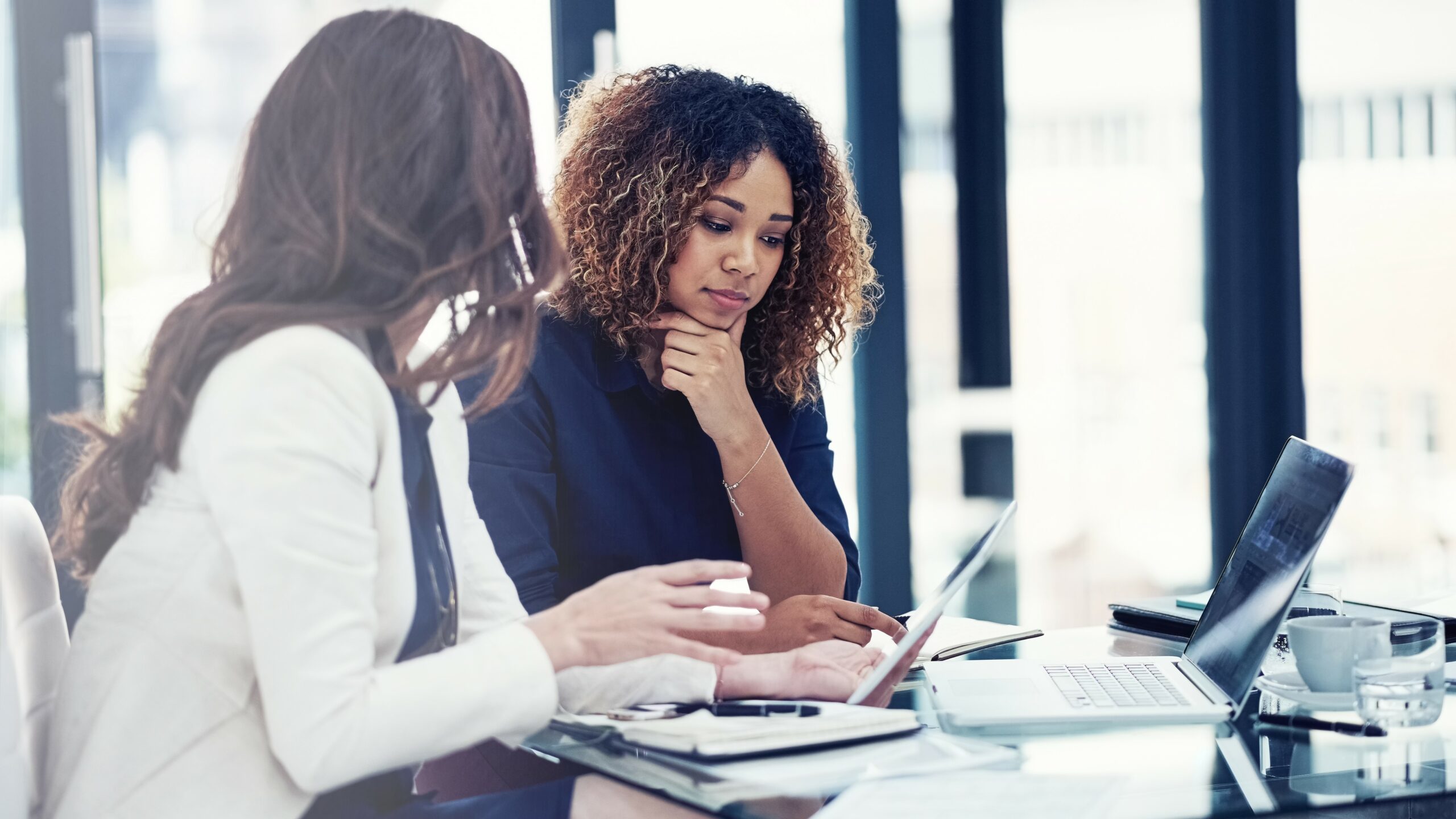 Shot of two businesswomen using a digital tablet together during a collaboration at work